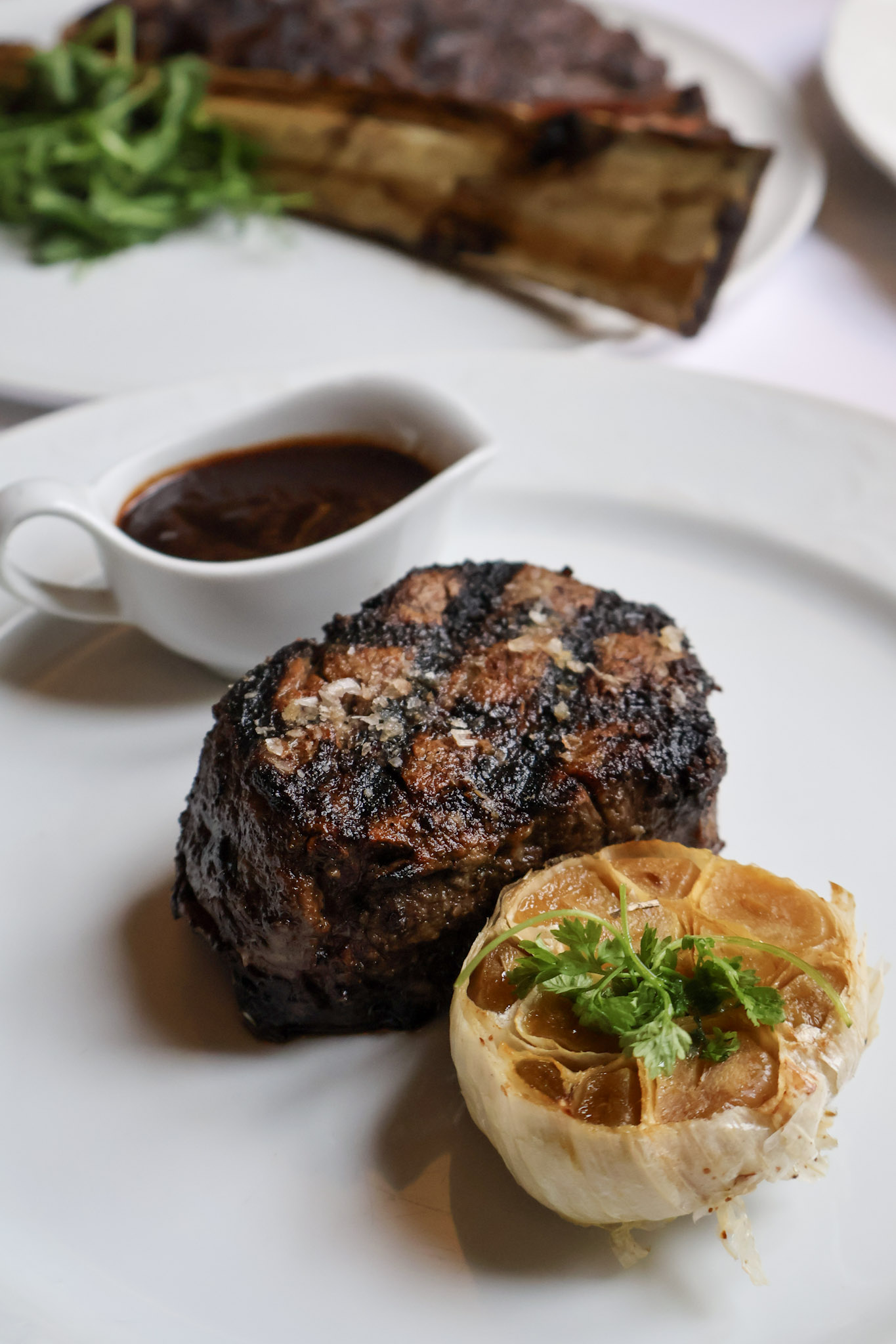 image of filet on plate with roasted garlic and housemade steak sauce